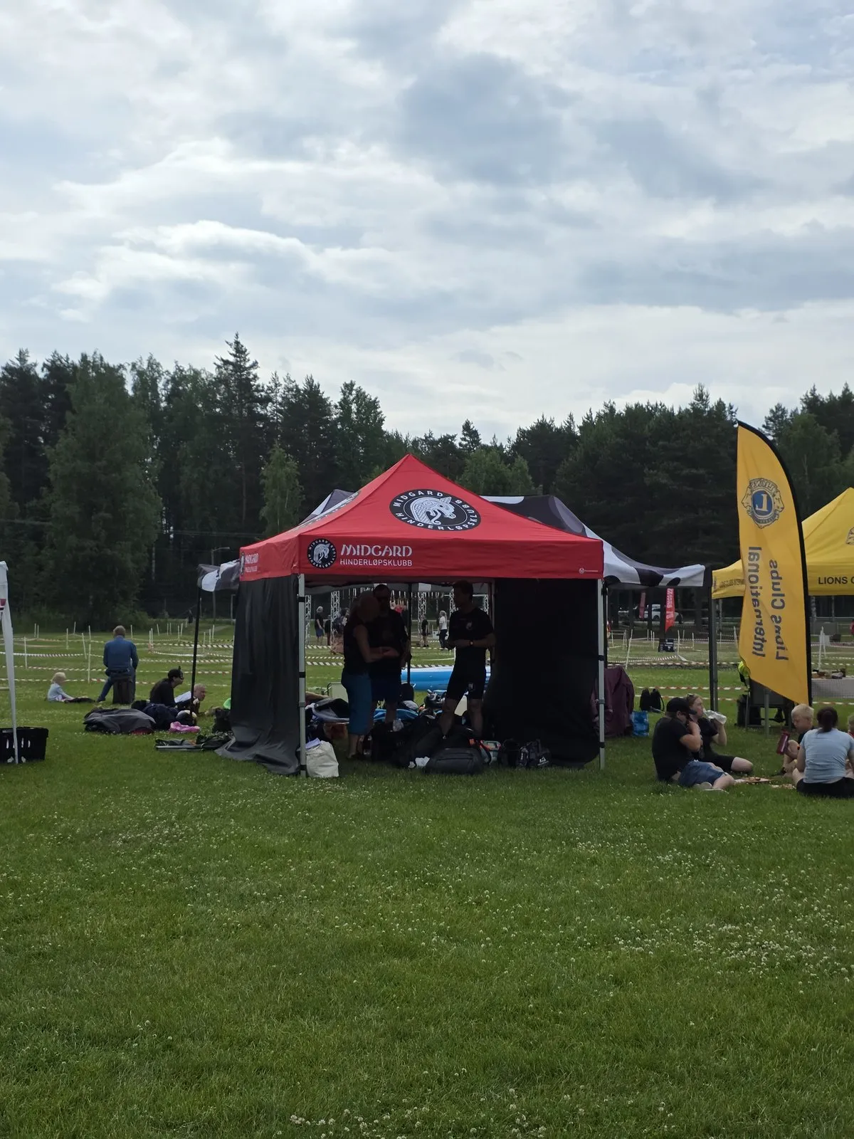 Midgards teamtelt på løpsområdet, med medlemmer som hviler i gresset